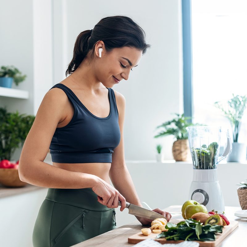 Woman in gym gear chopping fruit