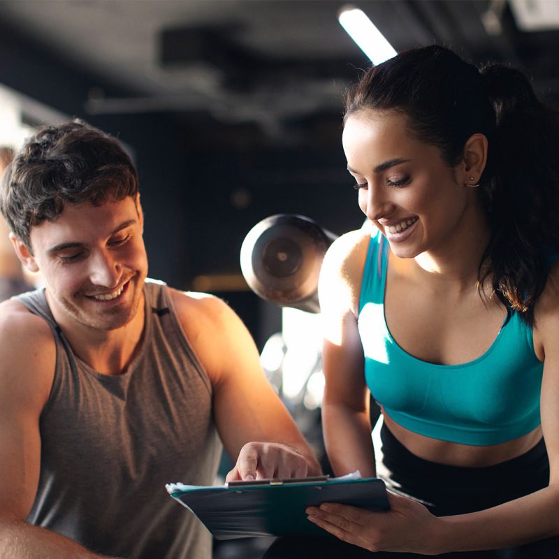 Man in gym giving female instructor feedback on iPad